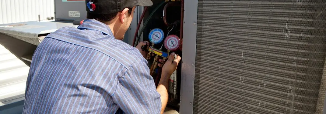 HVAC technician servicing a condenser unit in Winona